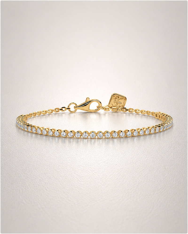 A delicate yellow-gold diamond tennis bracelet with a lobster clasp and a Culét signature tag