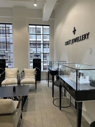 Inside the Culét Sydney showroom — black-framed windows, the CULÉT JEWELLERY wordmark on a cream wall, glass display cases, and a pair of cream upholstered armchairs